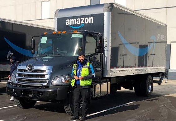 a man in a yellow vest standing next to an amazon truck