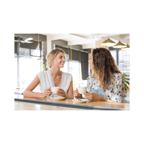 two women sitting at a table with coffee cups