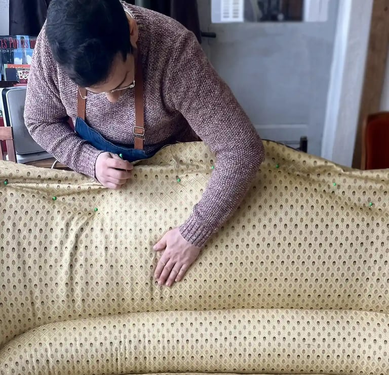 Un artisan couvre d'un tissu jaune à motifs un canapé