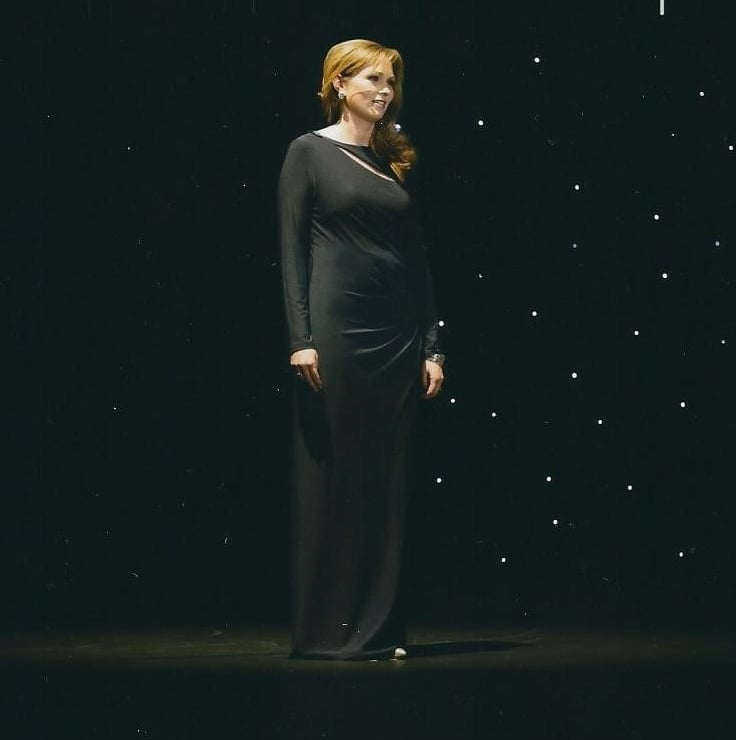 a woman in a black dress standing in front of a black background
