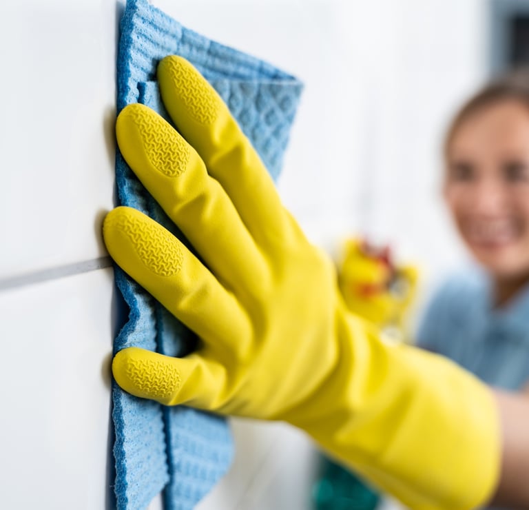 a woman in yellow gloves cleaning a wall