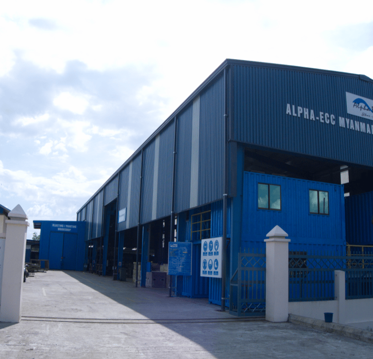 Alpha-ECC Myanmar industrial engineering facility showing exterior blue steel workshop building.