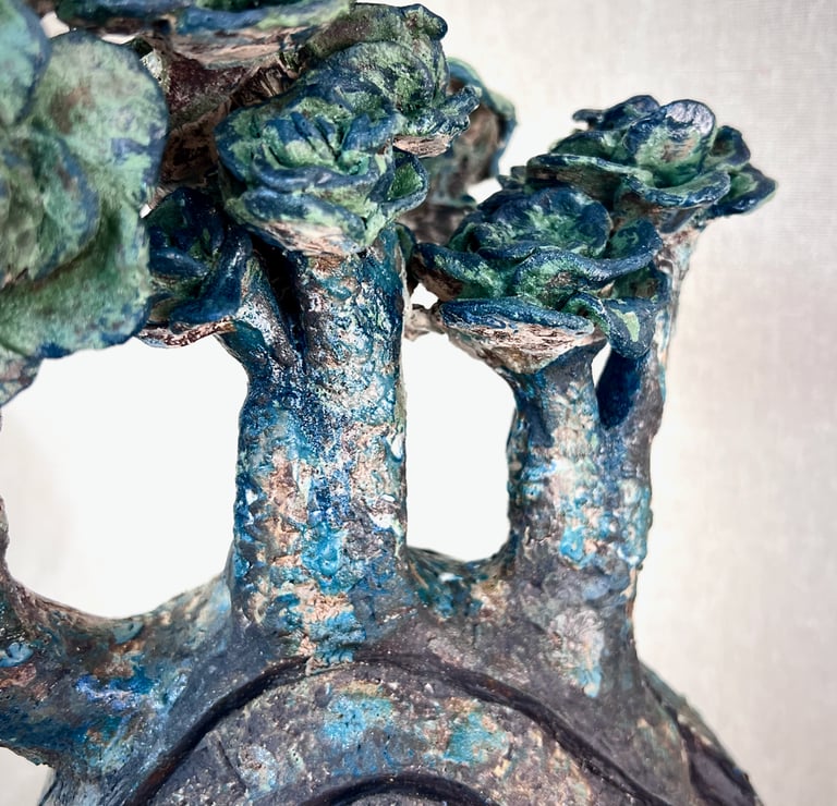 Abstract ceramic sculpture with blue and green glazes resembling textured trees and succulent flora.