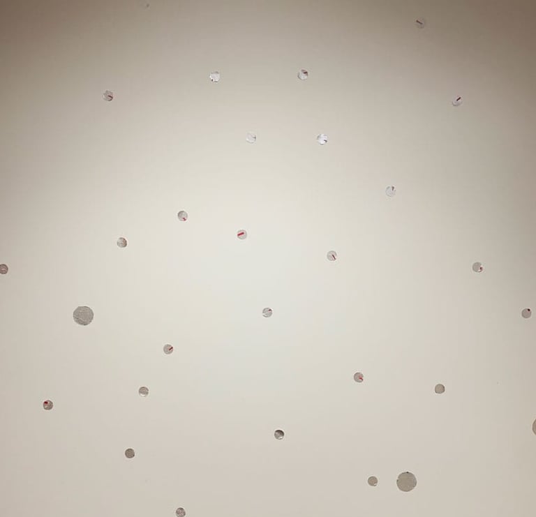 Multiple silver dot decals scattered in a playful pattern on a white background mural.