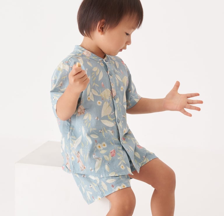 Menino asiático veste roupa com estampa de paisagem natural com animais e plantas