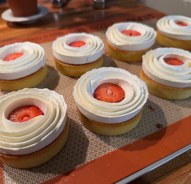 a tray of cupcakes with strawberries and cream