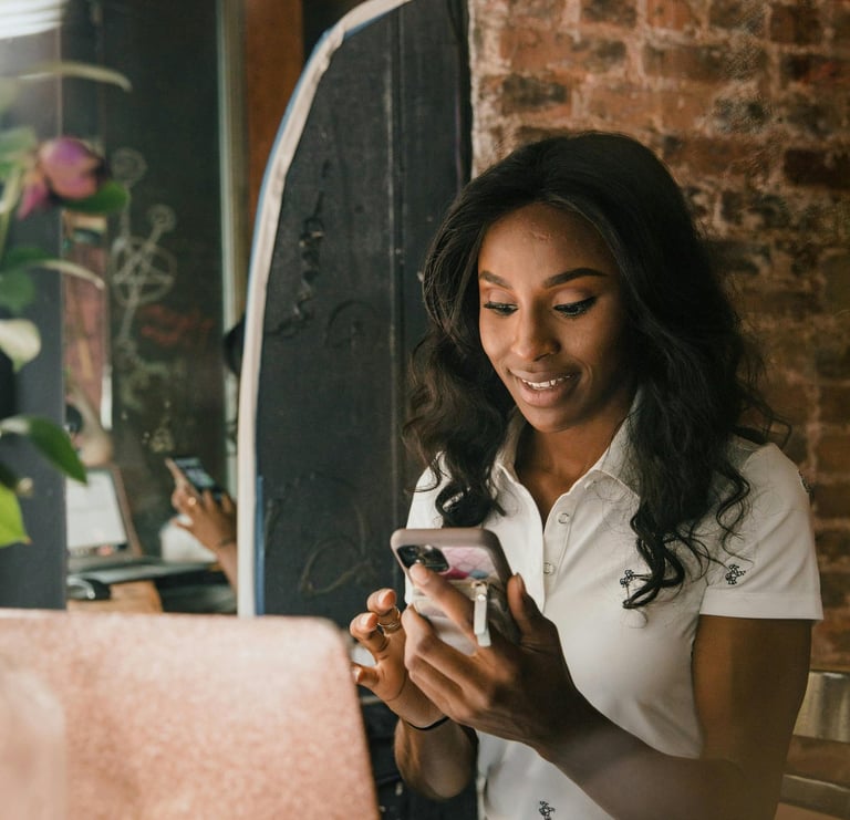 a woman sitting at a table with a laptop and a cell phone