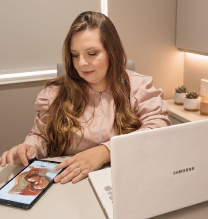 Fisioterapeuta analisando um tablet que mostra um útero com bebê.