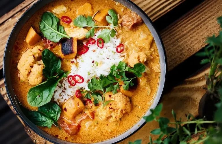 Coconut curry chicken in a bowl with spinach, herbs, and creamy sauce (THM S recipe).