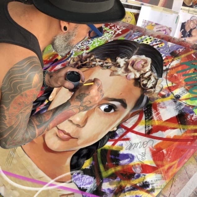 Sérgio Astral em seu estúdio, trabalhando em uma pintura à mão com tinta acrílica e spray.