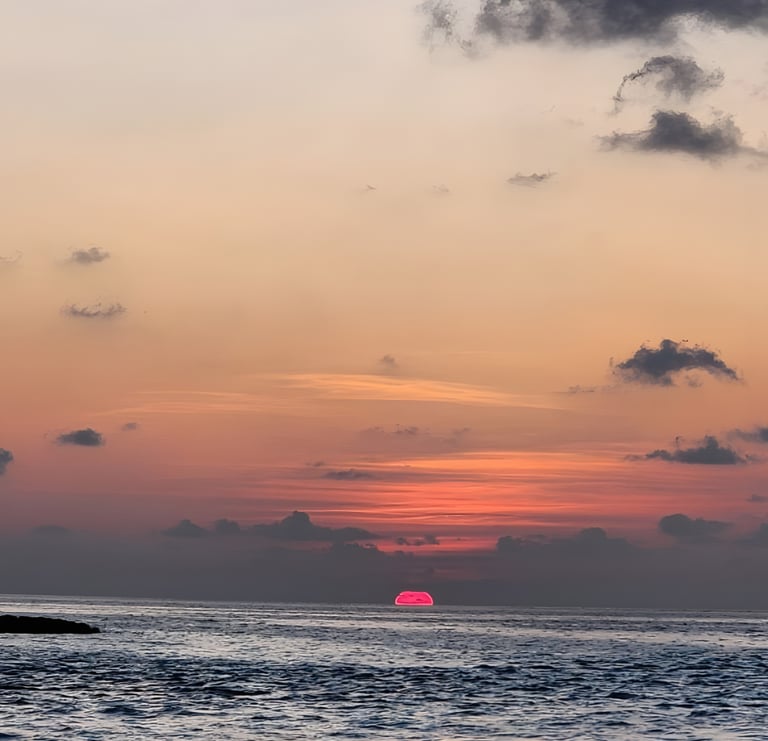 a sunset with a sailboat in the water