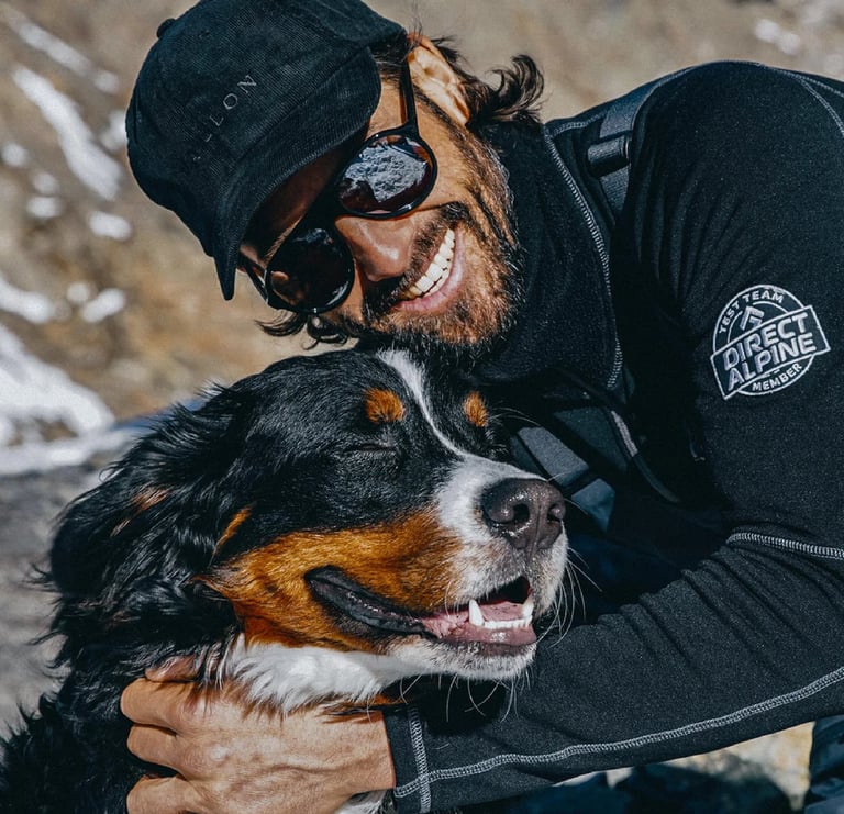 a man in a black jacket and sunglasses is holding a dog