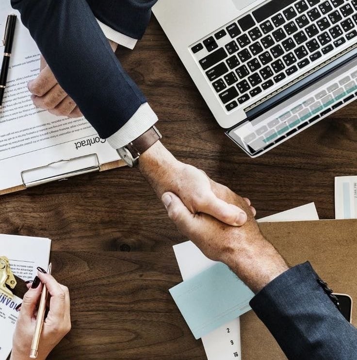 a group of people shaking hands over a desk