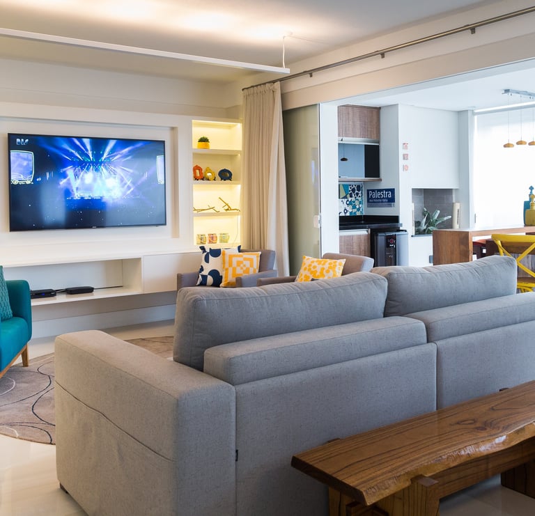 sala com televisão e sofá integrada com varanda e churrasqueira