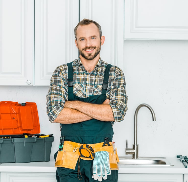 Professional home repair technician standing in a residential kitchen with tools