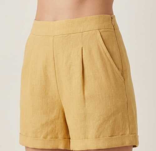 Short de lino amarillo mostaza de tiro alto, con pliegues frontales y bolsillos laterales.
