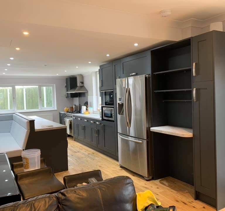a modern kitchen with a refrigerator, anthracite grey cabinets and seating