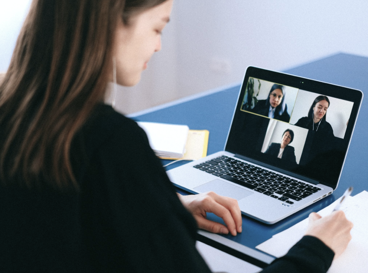A woman working remotely while attending a video conference call on her laptop.