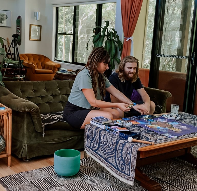 a woman and a man sitting on a couch doing a tarot oracle card reading