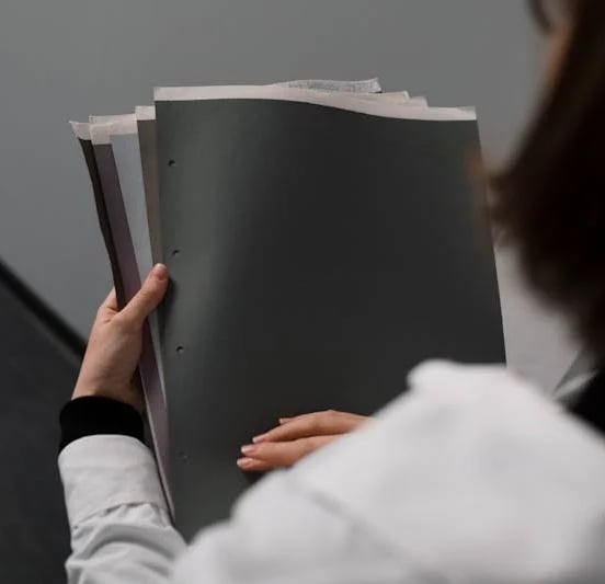 una mujer sosteniendo varias carpetas con documentos en las manos