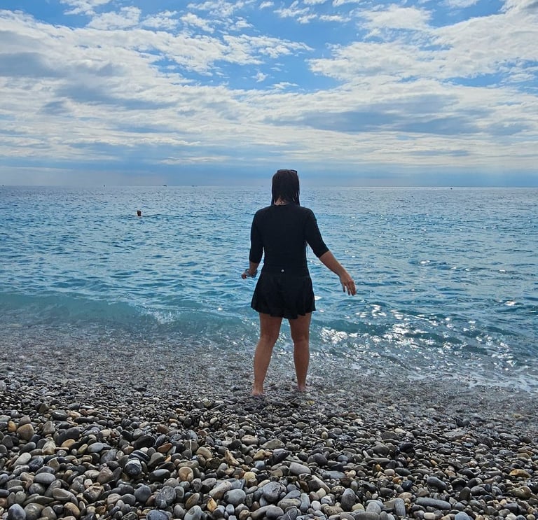 Girl in full coverage bathing suit steps into the Mediterranean in the South of France