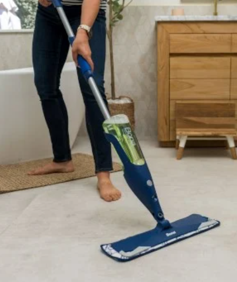a woman is cleaning a tile floor with a mop