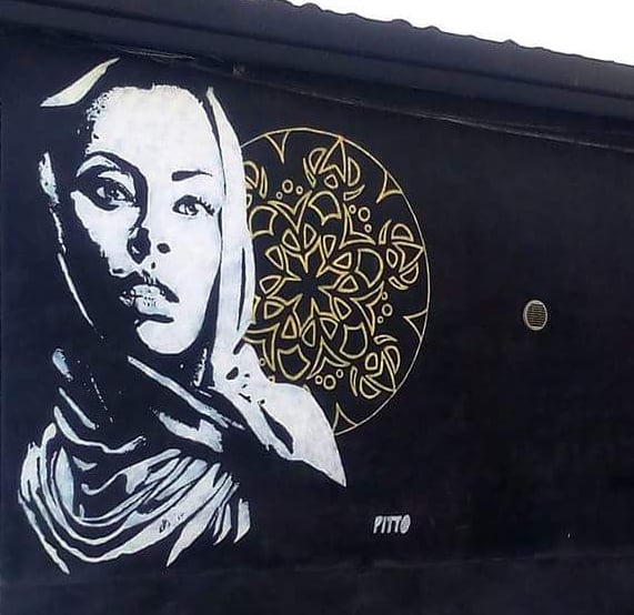 Black and white mural with female portrait and golden motif, created by Poliops.