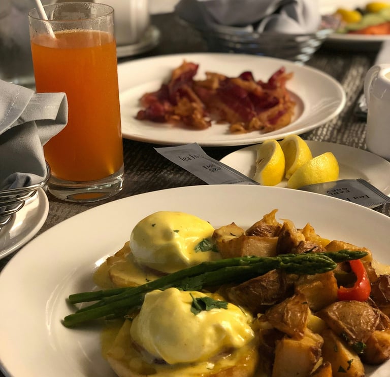 Hotel room service breakfast. Orange, bacon,potato, asparagus,lemon on plate.Guest Experience 