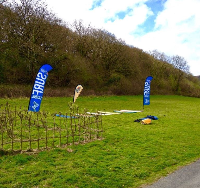 Surfboards laid on grass with surf school teardop flags