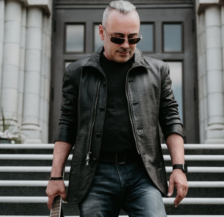a man in a leather jacket and sunglasses holding a guitar