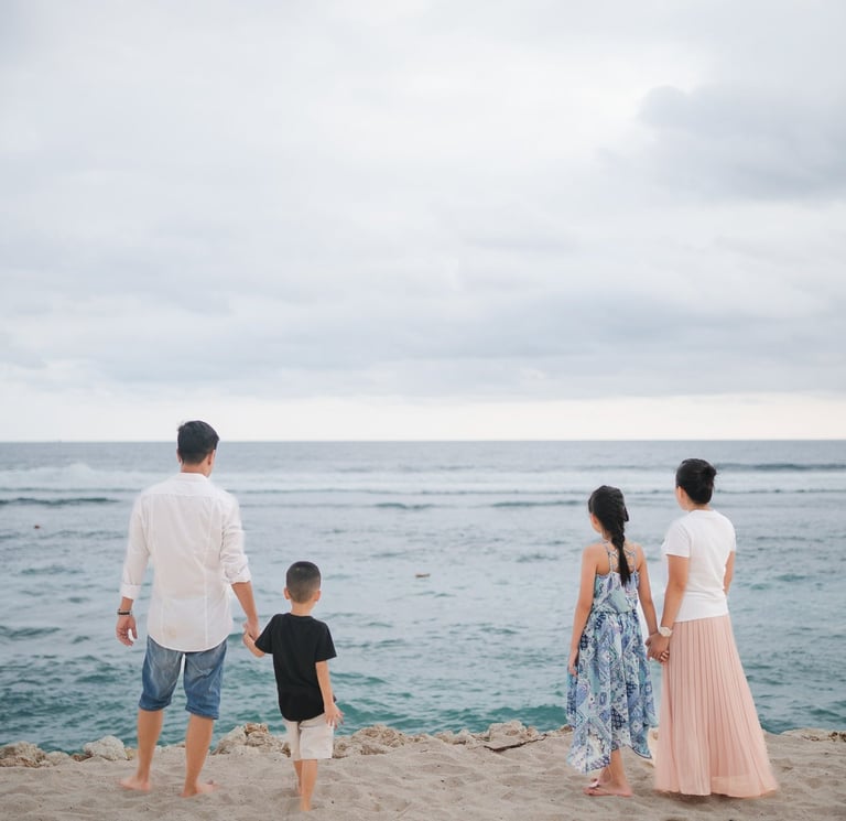 Family standing together along the cliffside coastline of Melasti Beach Bali during a relaxed family photography session