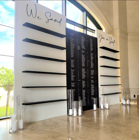 a black and white themed seating chart with candles and a we saved you a seat sign