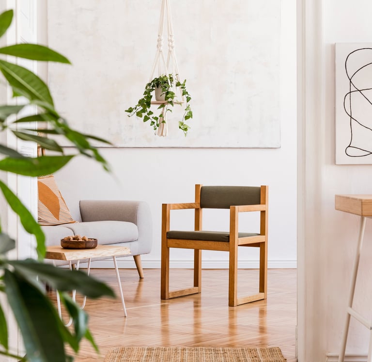Doorkijkje in kamer met vierkante houten stoel in het midden, een sterachtige plant linksvoor.