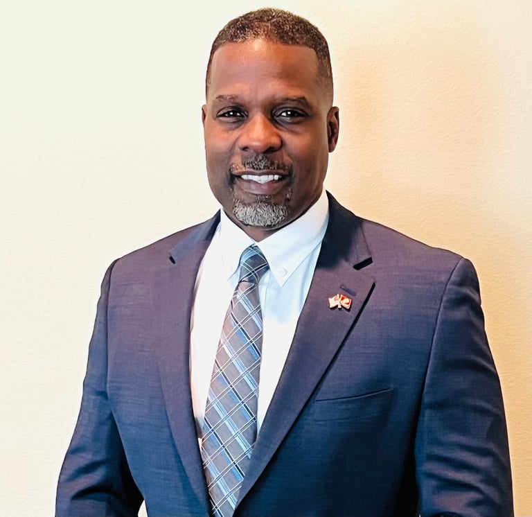 Dr. Marlon Ware standing in blue suit with blue striped tie