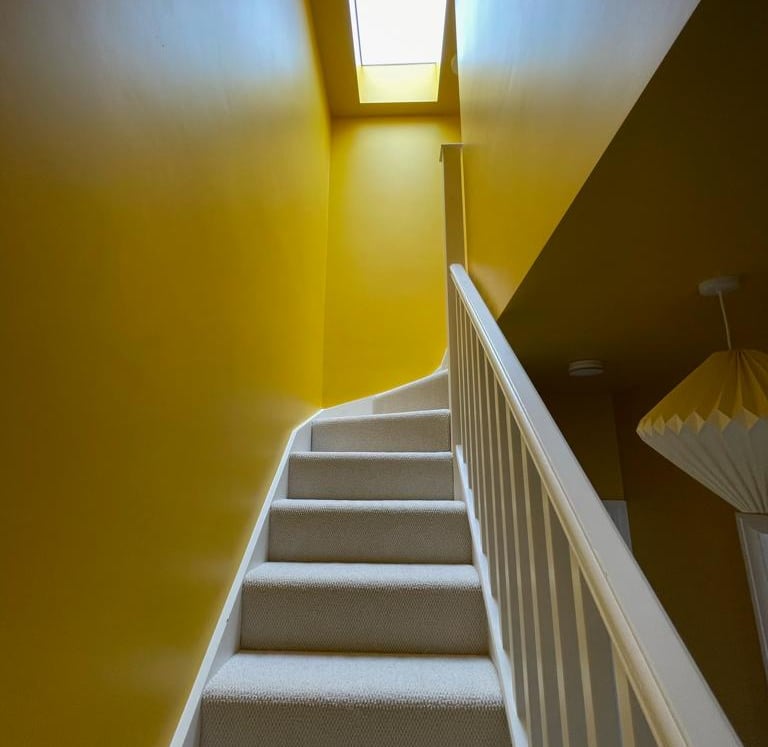 colour drenched stairwell to loft, bright yellow gloss paint and skylight creates very bright area