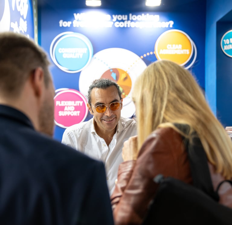 Matteo Borea smiling with customers during a coffee exhibition