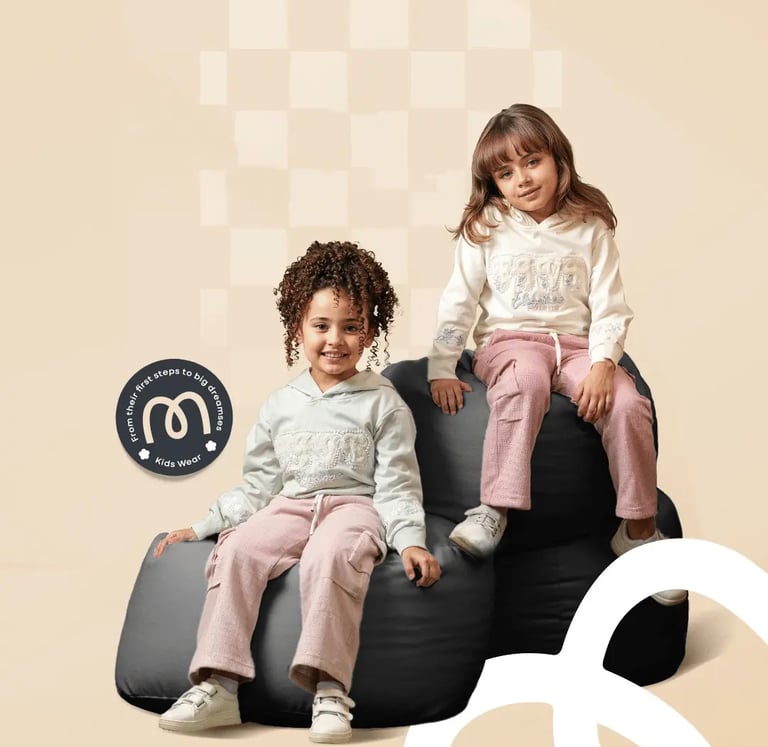 Two girls modeling Mab Kids Wear hoodies and pink jogger pants on black bean bags.