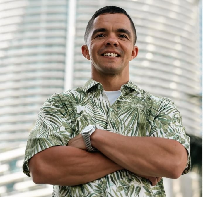Cody Sechelski in a hawaiian shirt and wearing a watch posing with a smile