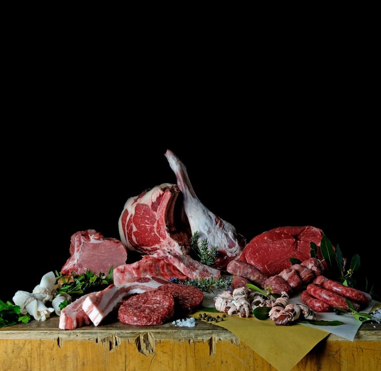 Variety of fresh raw meats including beef steaks, pork chops, and sausages on a rustic butcher block.