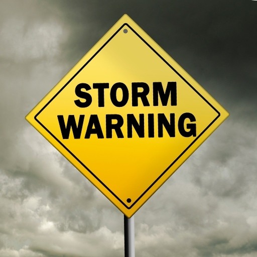 A yellow sign saying Storm Warning with stormy clouds in the background