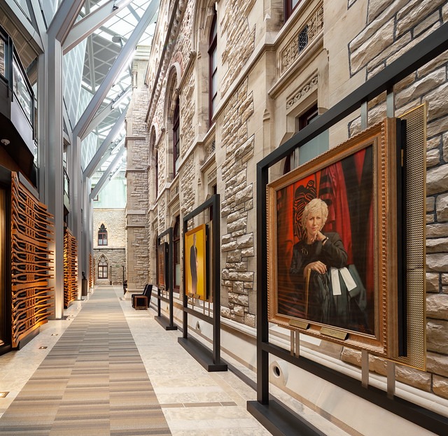 a hallway with a glass roof decorated with portrait art displays