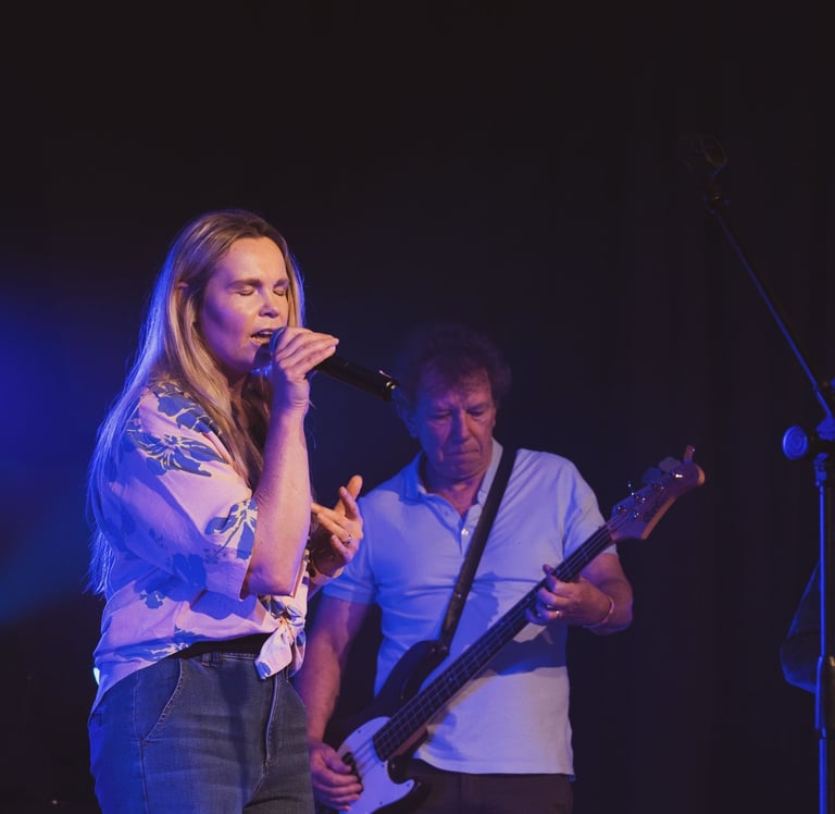 a woman singing into a microphone and a man playing the guitar