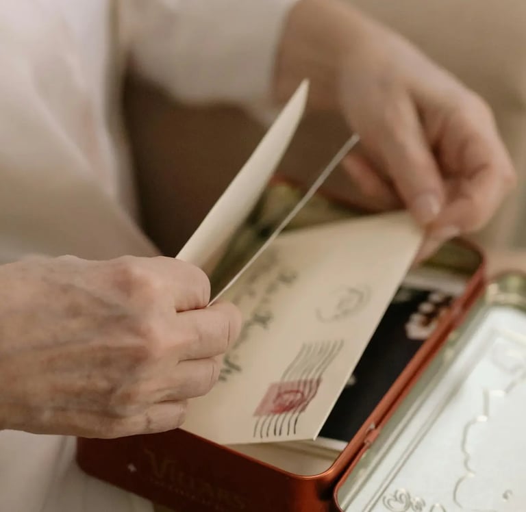 Hands opening a vintage metal tin filled with old letters and stamped envelopes.