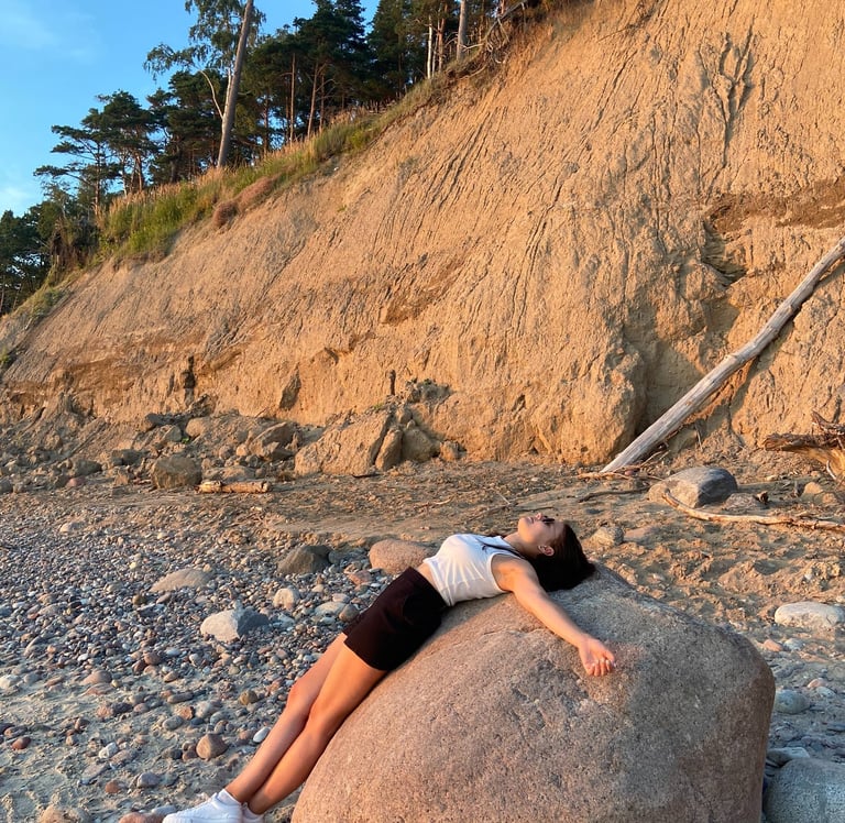 A picture of a woman laying on rock on a beach