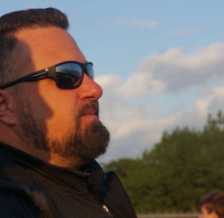 a man with a beard and sunglasses on a sunny day