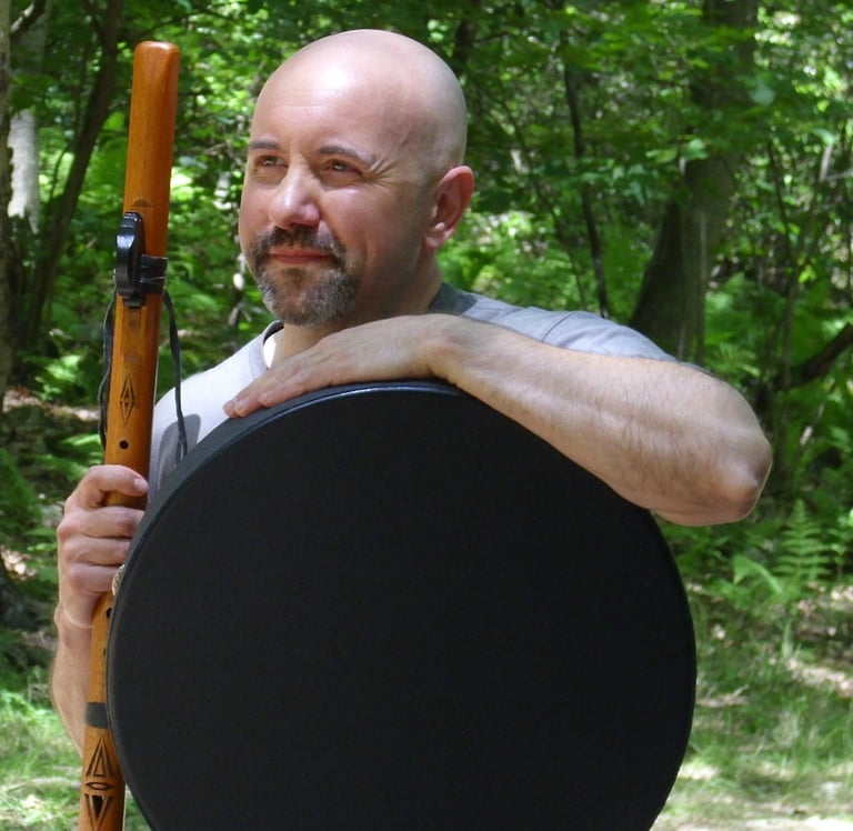 Incredibly handsome bald guy holding a flute and drum.