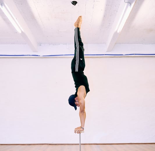 Man voert een rechte handstand uit op canes bij De Polecats Fabriek in Gent