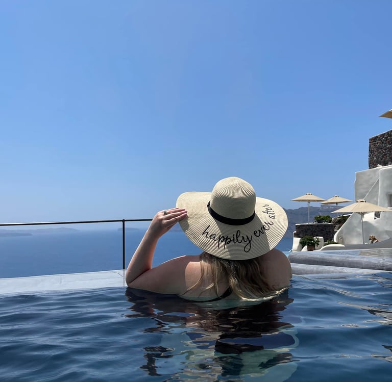 The back of a woman in a pool wearing a large sun hat 