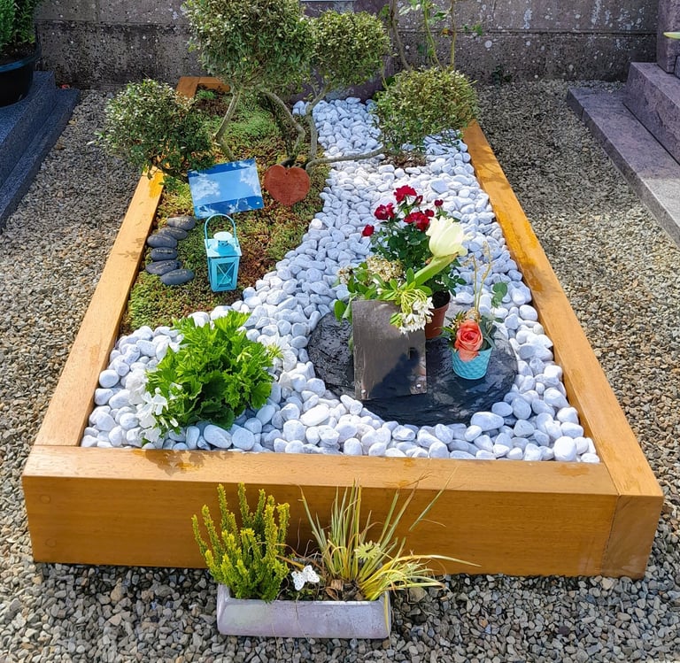 Jardin du souvenir avec cadre bois, décor de galets blancs sinueux et artopierre