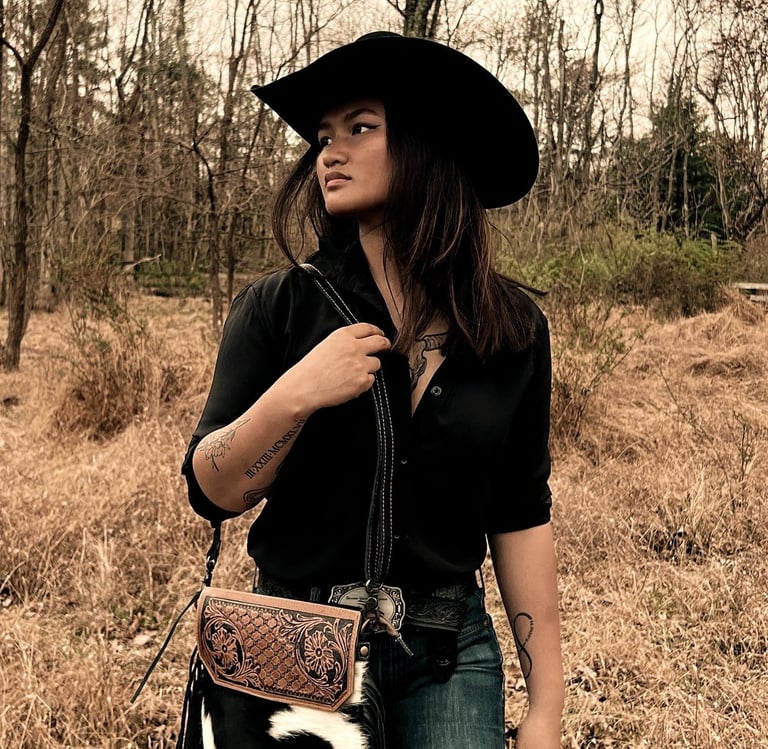 Woman in a black top and black cowboy hat walking in the woods